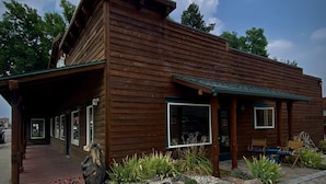 Eine Holzhütte mit verdeckter Veranda, großen Fenstern und rustikalem Aussehen.