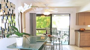 A modern kitchen with a glass island, wooden cabinets, and a dining area with chairs and a table. - South Palm Springs Resort-Style Getaway (Palm Springs)