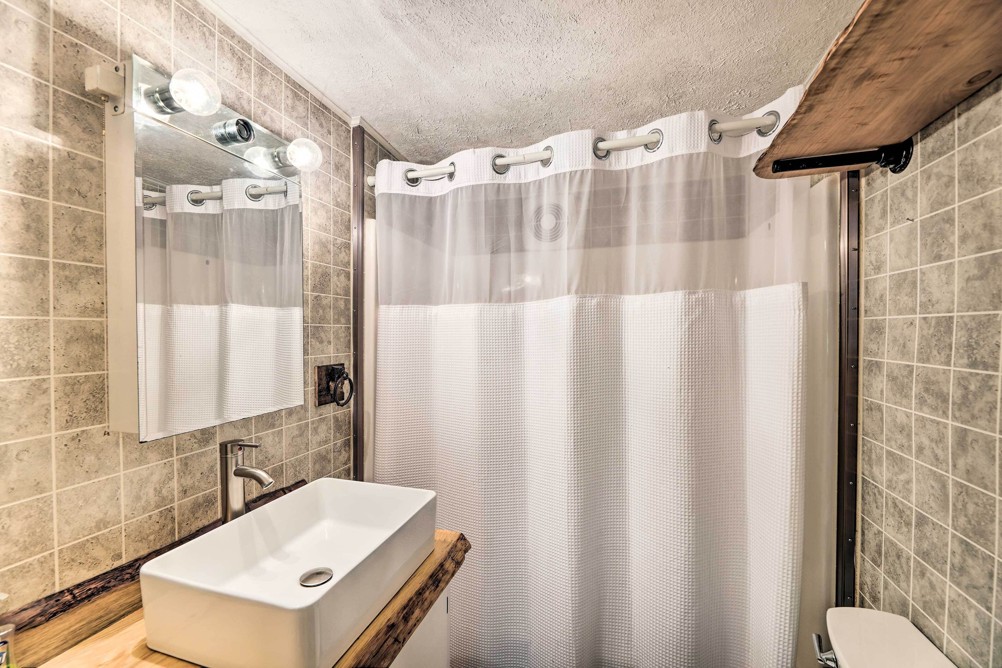 Une salle de bain avec un lavabo rectangulaire, un miroir et un rideau de douche.
