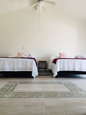 A room with two beds, a small table, and a ceiling fan. - House buganvilias in hotel zone Cancún, with pool (Cancún)
