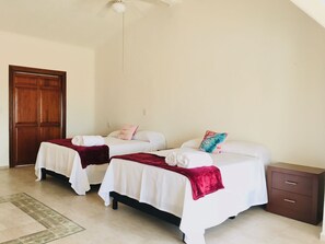 A room with two beds, a wooden door, a small cabinet, and a ceiling fan. - House buganvilias in hotel zone Cancún, with pool (Cancún)