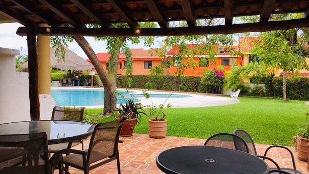 An outdoor patio with a pool, surrounded by orange buildings and green lawns.