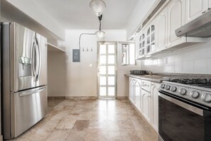 A modern kitchen with stainless steel appliances, white cabinetry, and a marble floor. - Casa Azura - 4BR Pool Villa · Sleeps up to 16 (Cancún)