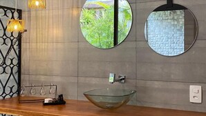 A bathroom with a wooden vanity, a glass bowl sink, and two round mirrors with black frames. - Estalagem Alter Real (Pirenópolis)
