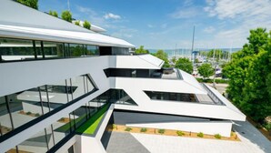 A modern building with a glass facade, multiple levels, and a rooftop garden. - Apartment Fűzfő by Interhome (Balatonszemes)
