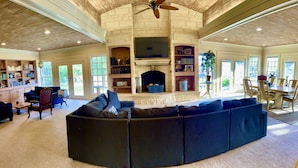 A spacious living room with a fireplace, a large sectional sofa, and a dining area with a table and chairs. - Historic 1906, 15 acre Ranch with pool 20 minutes from SeaWorld (San Antonio)