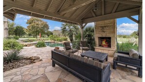 An outdoor patio with stone flooring, a fire pit, and seating. - Historic 1906, 15 acre Ranch with pool 20 minutes from SeaWorld (San Antonio)