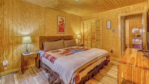Une chambre à coucher aux murs lambrissés, avec un lit, des tables de chevet et une commode.