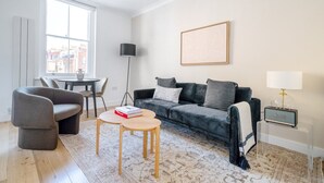 Una sala de estar moderna con sofá, sillón, mesa de centro, lámpara de pie y un radio.