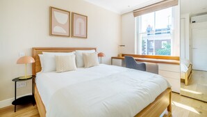 Una habitación de hotel moderna con una cama grande, un escritorio y una ventana con vistas a la ciudad.