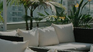 Ein Balkon mit einer Couch und Topfpflanzen mit Blick auf eine Stadtlandschaft.