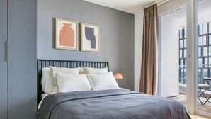 Une chambre à coucher moderne avec un lit, des murs gris et une grande fenêtre.