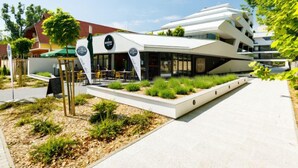 A modern building with a cafe area, outdoor seating, and a landscaped garden. - Földvár by Interhome (Balatonszemes)