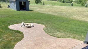 A concrete patio with a curved edge, leading to a grassy yard. - All Amenities!  Salt water hot tub!  Walking trail!  In town! (Spearfish)