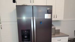 A stainless steel refrigerator with a water dispenser, white cabinets, and a microwave above it. - Pensacola Breeze/ Downtown (Pensacola)
