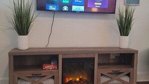 A flat-screen TV mounted on a wooden entertainment center with two potted plants on either side. - Pensacola Breeze/ Downtown (Pensacola)