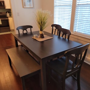 Una mesa de comedor con cuatro sillas, un florero con una planta y un mantel individual.