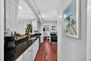 A modern kitchen with white cabinets, a black countertop, and a stainless steel oven.