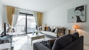 Ein modernes Wohnzimmer mit einer Couch, einem Couchtisch und einem Balkon mit Vorhängen.