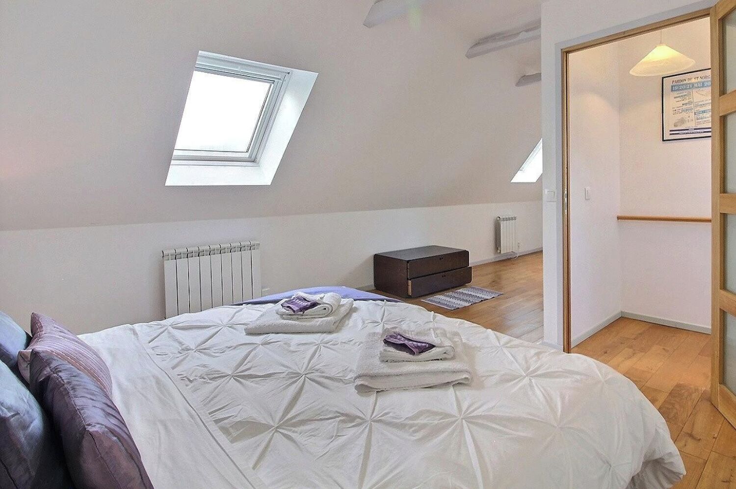 Ein Schlafzimmer mit Dachfenster, Heizkörper, Nachttisch und Kleiderschrank.
