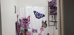 Een badkamer met een douchegordijn met een bloem- en vlinderprint.