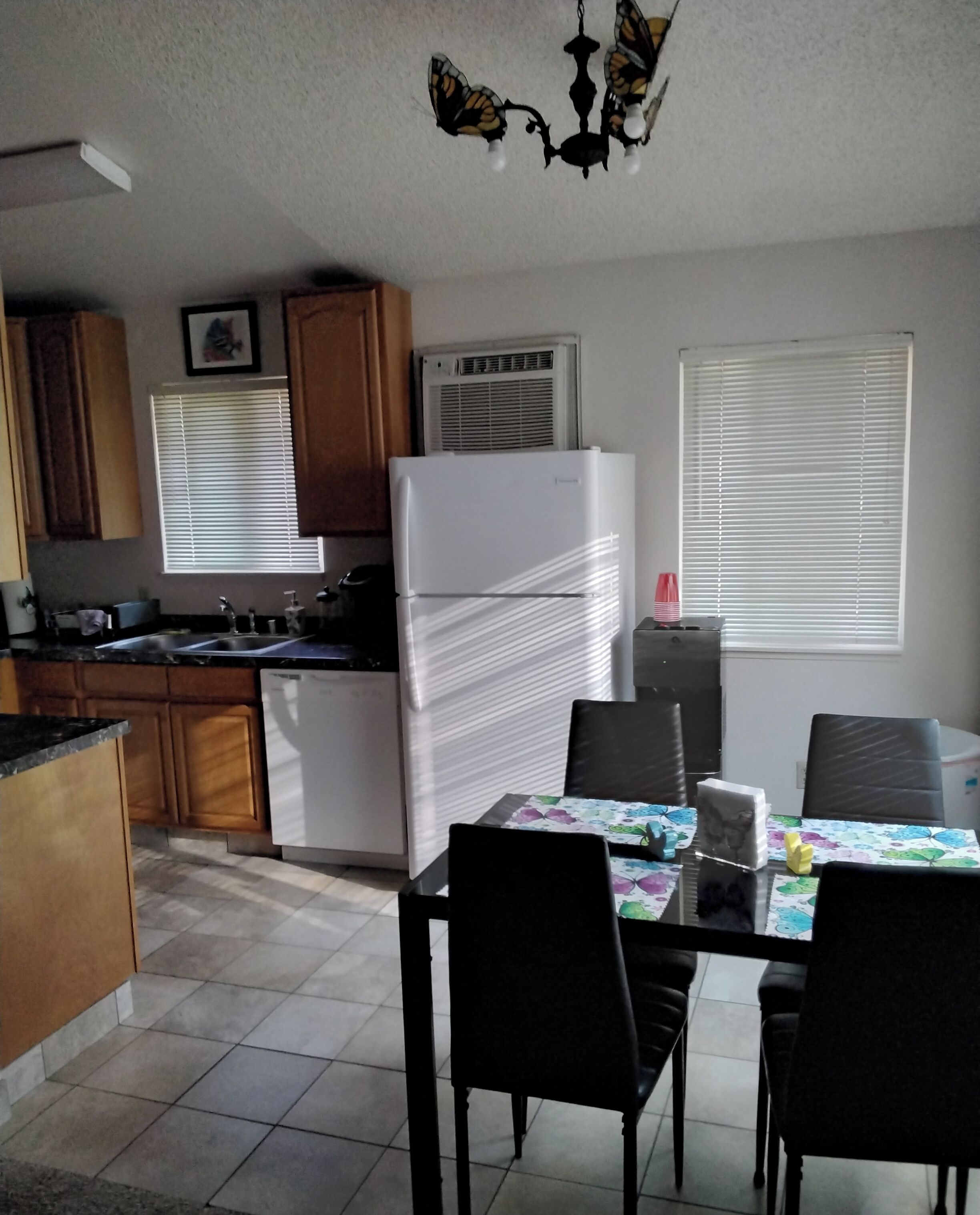 A kitchen with a white refrigerator, wooden cabinets, a dining table with chairs, and a chandelier.