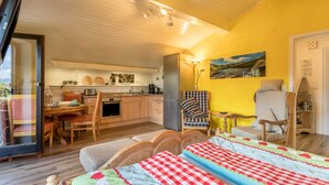 Una habitación acogedora con cama, sillón, mesita y espacio de cocina.