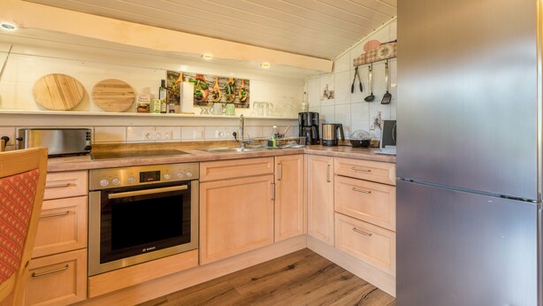 Una cocina moderna con armarios de madera, electrodomésticos de acero inoxidable y suelo de madera.
