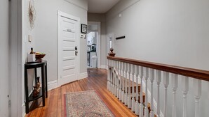 A hallway with a wooden floor, a white door, a black console table, and a patterned rug. - Carytown Gem | Spacious Family-Friendly Apartment (Richmond)