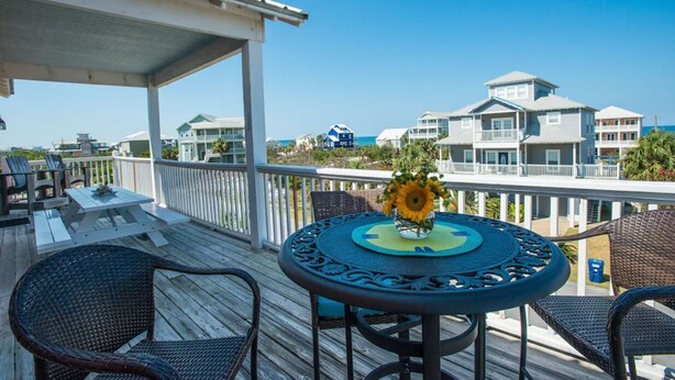 A wooden deck with a table and chairs, overlooking a beachfront with multiple houses. - Dates Available!!  Check out our property!! (Port St Joe)