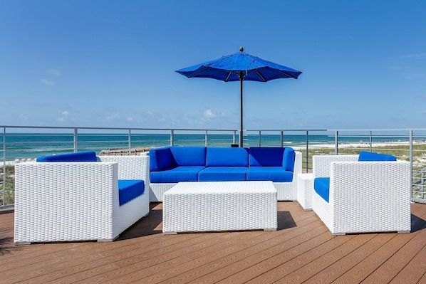 A deck with a blue sofa, two white armchairs, and a matching coffee table.