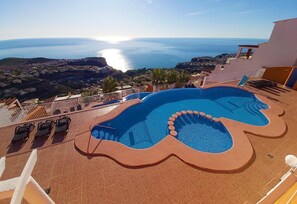 Une piscine sur le toit, dotée d’un design original, offrant une vue imprenable sur une ville côtière et la mer.