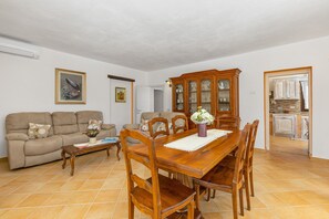 A living room with a sofa, dining table, chairs, and a cabinet.