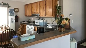 A kitchen with wooden cabinets, a stove, a sink, and a water dispenser. - Bright and cheerful. With glorious sunrise/sunset views, close to Glacier park. (Columbia Falls)