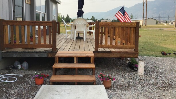 A wooden deck with a bench, a table, and a potted plant. - Bright and cheerful. With glorious sunrise/sunset views, close to Glacier park. (Columbia Falls)