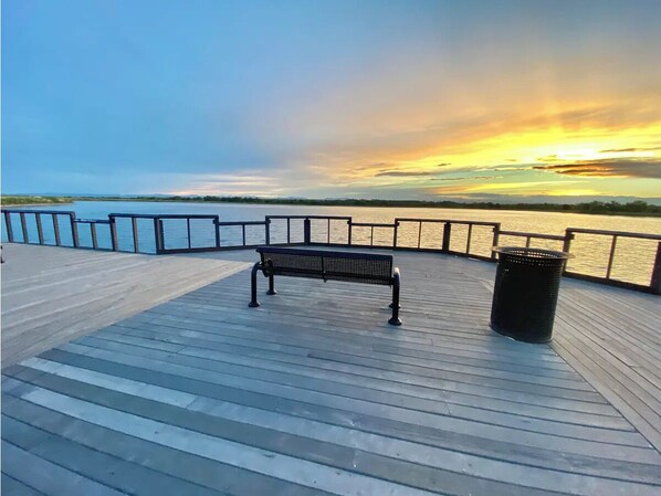 Enjoy the serene waterfront view from this deck, which offers a bench and trash can.