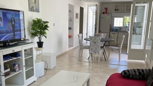 Een ruime woonkamer met een televisie, een eethoek en een keuken.