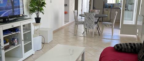 Un salón amplio con televisor, comedor y cocina.