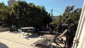 Een patio met een ronde tafel en stoelen, een rieten bank en een metalen stoel.