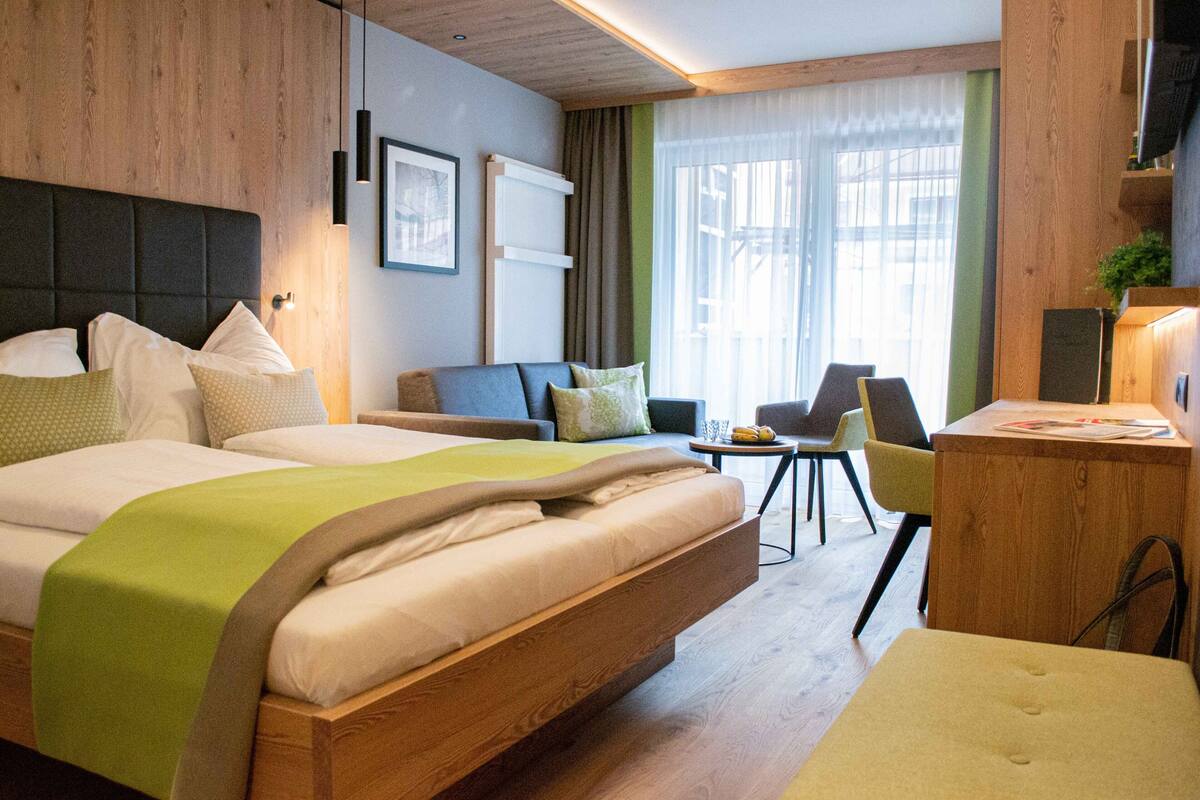 A modern hotel room with a large bed, a desk, and a seating area.