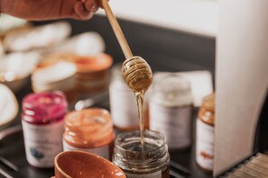 A hand holding a honey dipper dripping honey into a jar. - FIRSTpeak (Altenmarkt im Pongau)