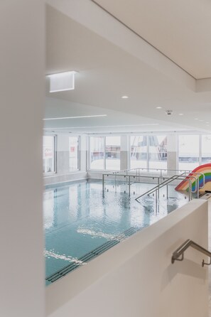 A swimming pool with a slide, large windows, and a view of the outside. - FIRSTpeak (Altenmarkt im Pongau)