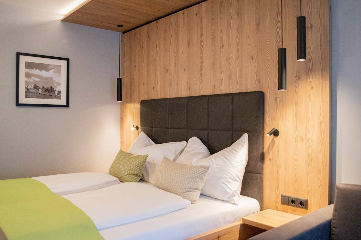 A double bed with a wooden headboard, two bedside tables, and a framed picture on the wall.