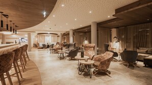 A modern lounge area with bar seating, round tables, and comfortable chairs. - FIRSTpeak (Altenmarkt im Pongau)