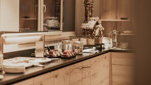 A breakfast bar with various food items and utensils, wooden cabinets, and a decorative Christmas tree in the background. - FIRSTpeak (Altenmarkt im Pongau)