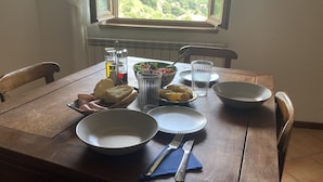 Una mesa de madera con platos, pan, una ensaladera y aderezos.