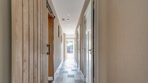 Un pasillo con paneles de madera en un lado y una pared texturizada en el otro, que conduce a una habitación luminosa con vistas.