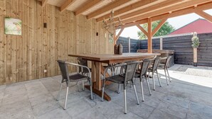 Una pérgola de madera al aire libre con una mesa y sillas para comer.