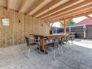 Eine hölzerne Pergola im Freien mit Esstisch und Stühlen.