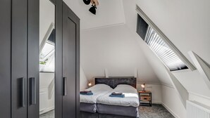 Un dormitorio con cama, armario, mesita de noche y tragaluz.